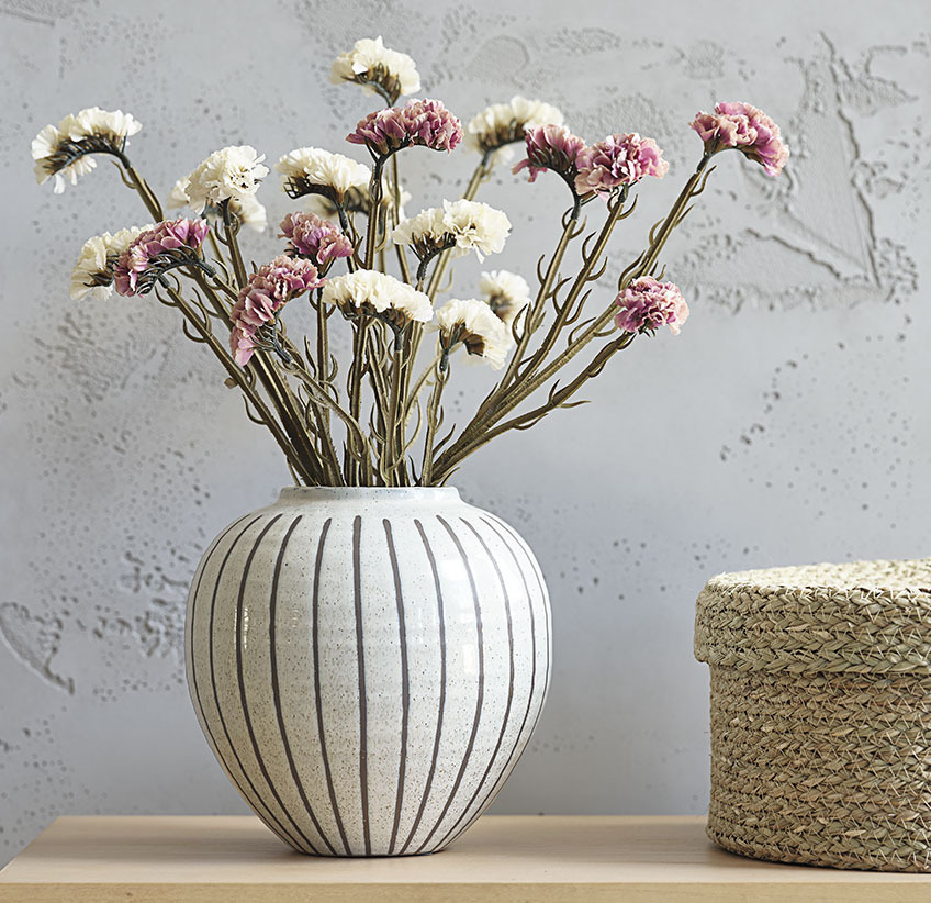 Roos en witte kunstbloemen in witte vaas met grijs streeppatroon