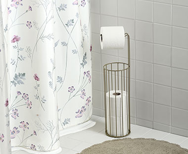 Douchegordijn met paarse bloemetjes en een toiletrolhouder