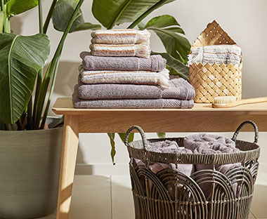 Handdoeken opgevouwen op een bankje, grote mand en kleine mand