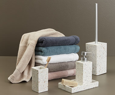Handdoeken in diverse kleuren met witte marmeren zeepdispenser, toiletboorstel- en tandenborstelhouder