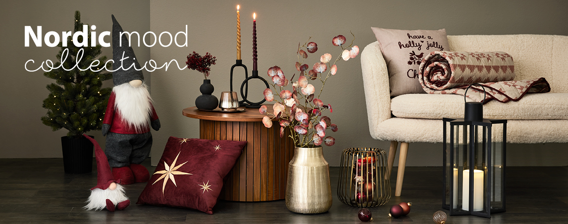 Kerstelfjes, kussens, gouden vaas met kunstbloem, gouden kandelaar en zwarte lantaarn voor een witte bank