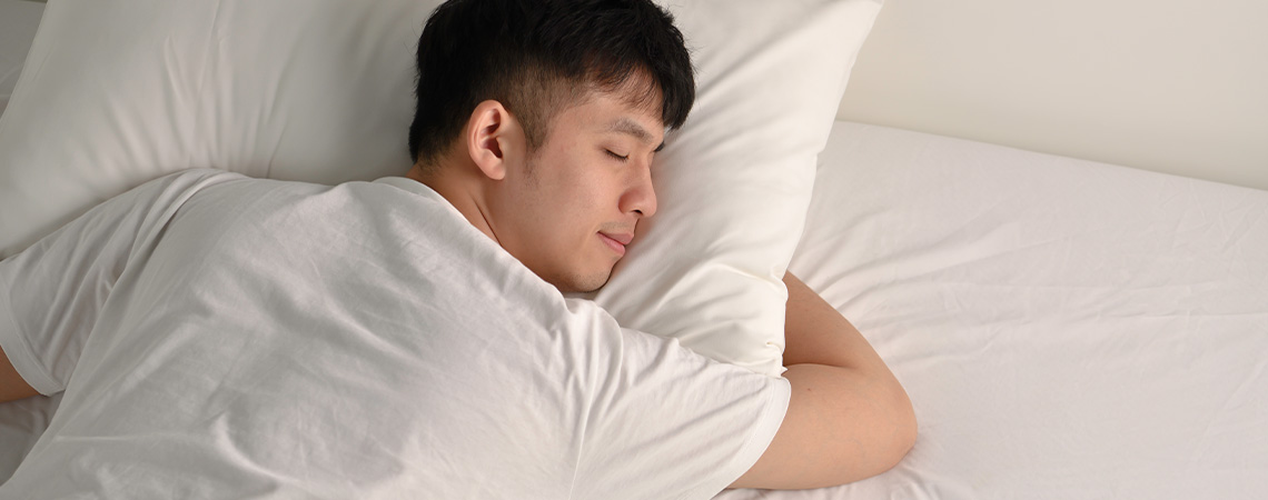 Rustig slapende man in bed met wit kussen en wit topmatras