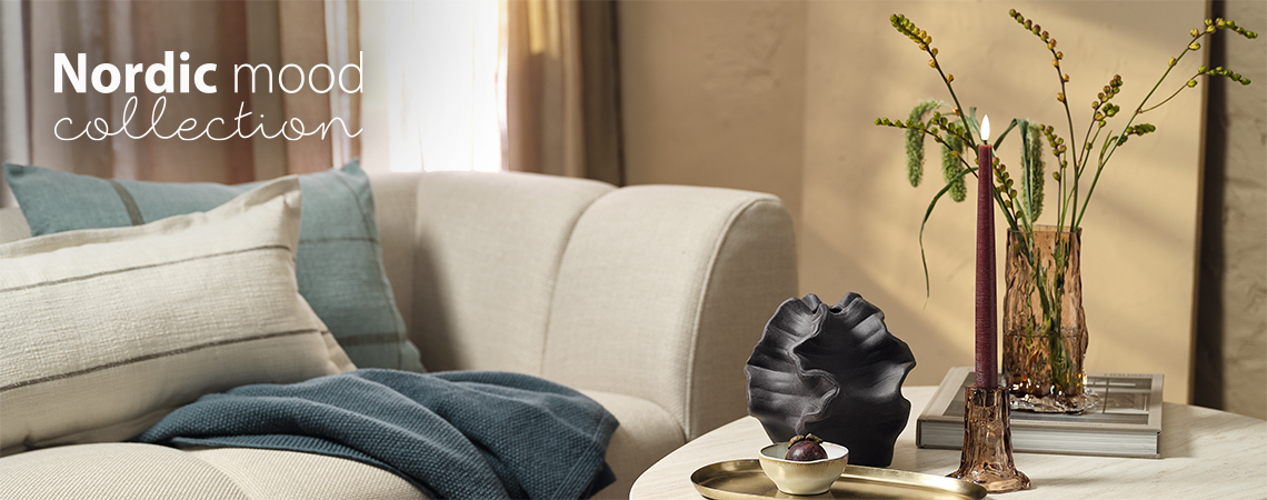 Woonkamer met een bank en salontafel met een glazen vaas en een kandelaar 