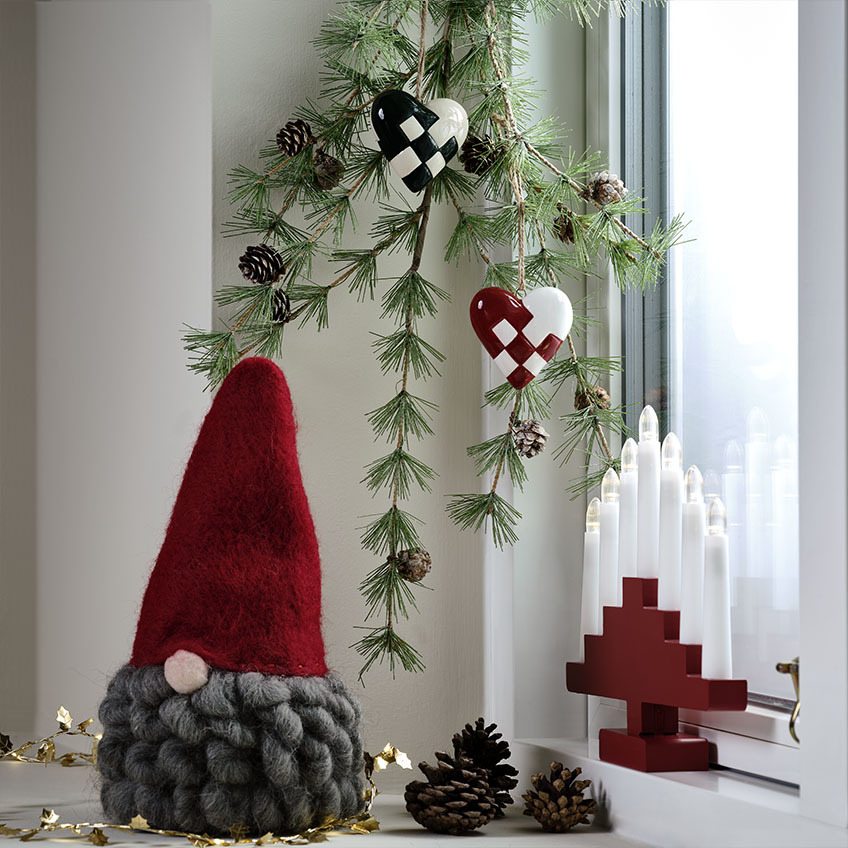 De MUGGLESTEN kerstman heeft een grote, krullende baard Scandinavische kerstman met grijze baard op een versierde vensterbank