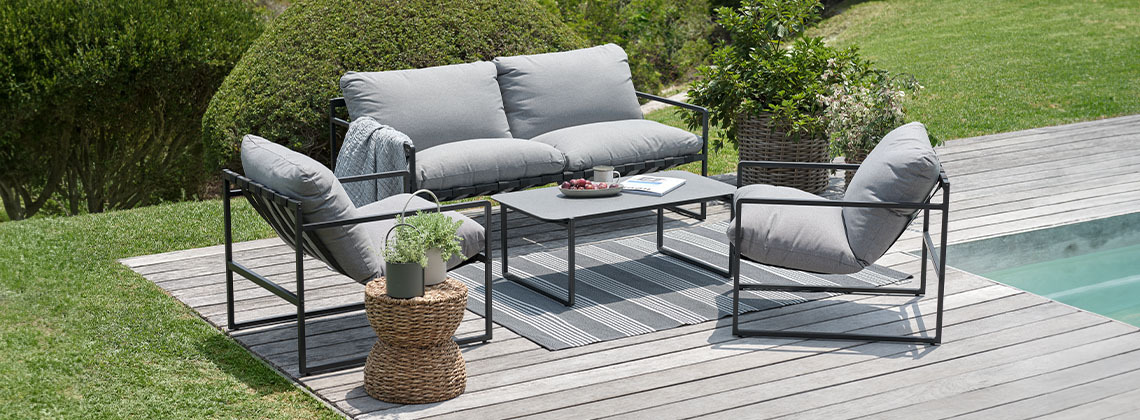 Loungeset met loungebank, loungestoelen en loungetafel in tuin naast zwembad