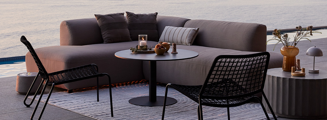 Sneldrogende loungebank voor alle weersomstandigheden en tuinstoelen op terras bij zonsondergang