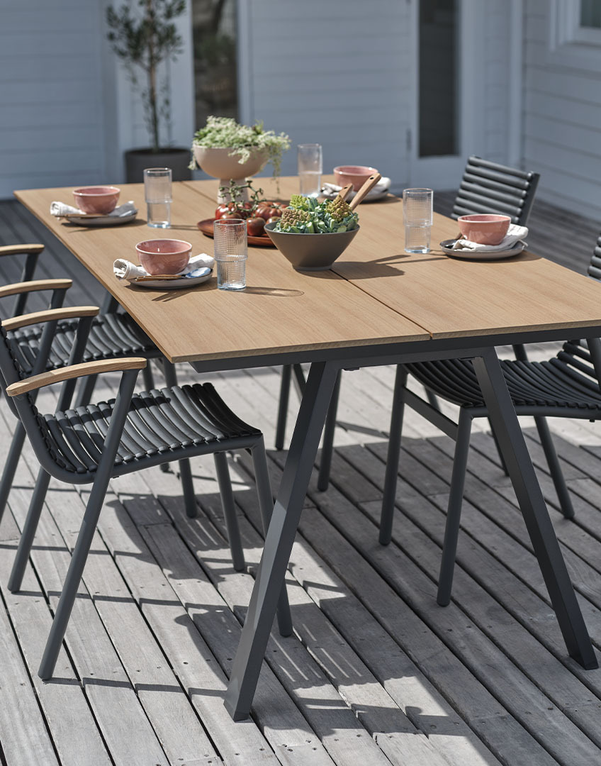 Tuintafel met tafelblad van kunsthout en stapelbare kunststof stoelen met armleuningen van gerecycled teakhout 