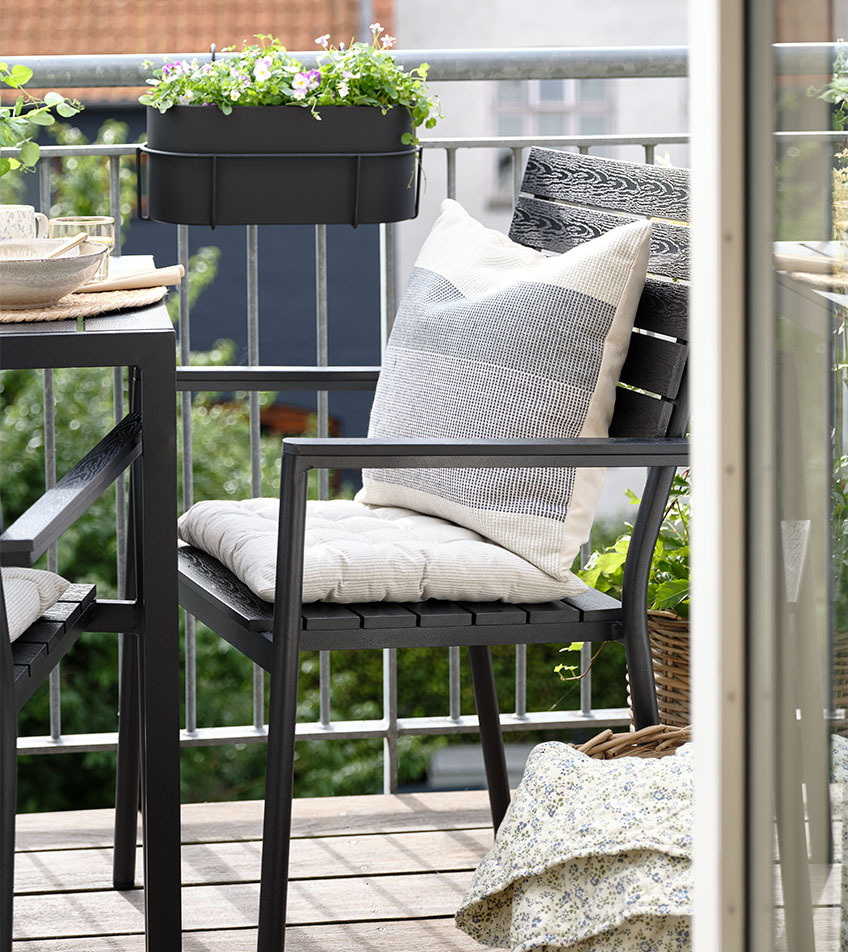 Zwarte stapelbare tuinstoel met kussens op balkon