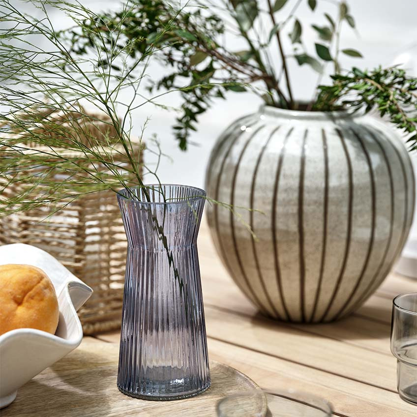 Vazen, lantaarn en schaal op houten tuintafel buiten 