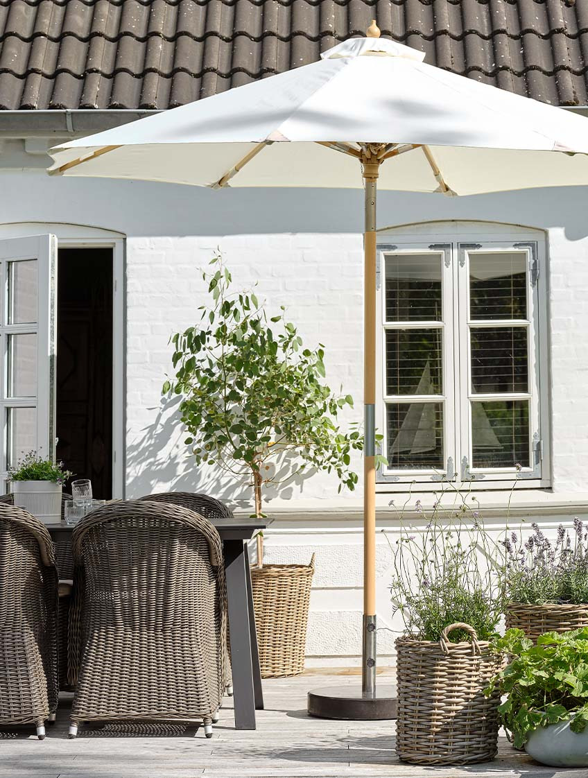 Klassieke off-white tuinparasol op patio met tuintafel en tuinstoelen