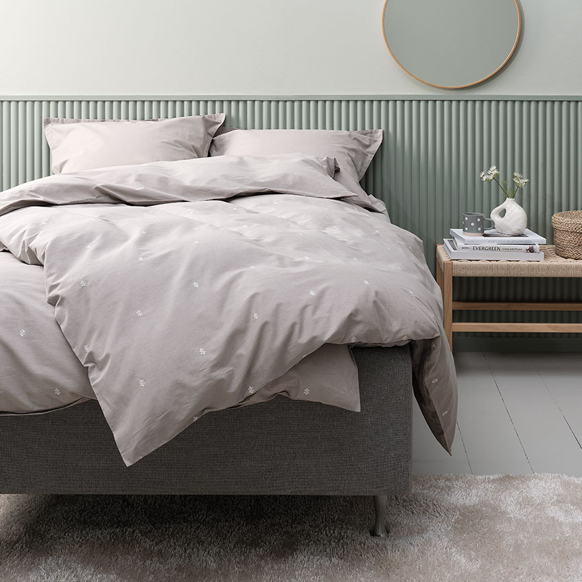 Lichtgrijs dekbedovertrek en katoenen beddengoed inclusief kussensloop op bed in slaapkamer