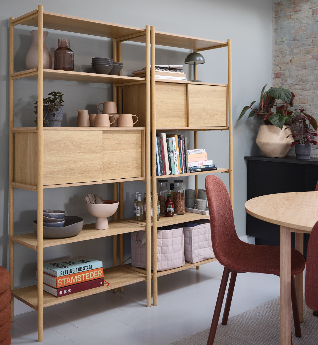 Wandrek met diverse decoratie, een batterijlamp en een eettafel met eetkamerstoelen