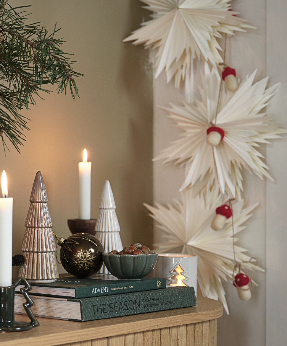 Een dressoir met mooie kerstversieringen en papieren sterren langs de muur