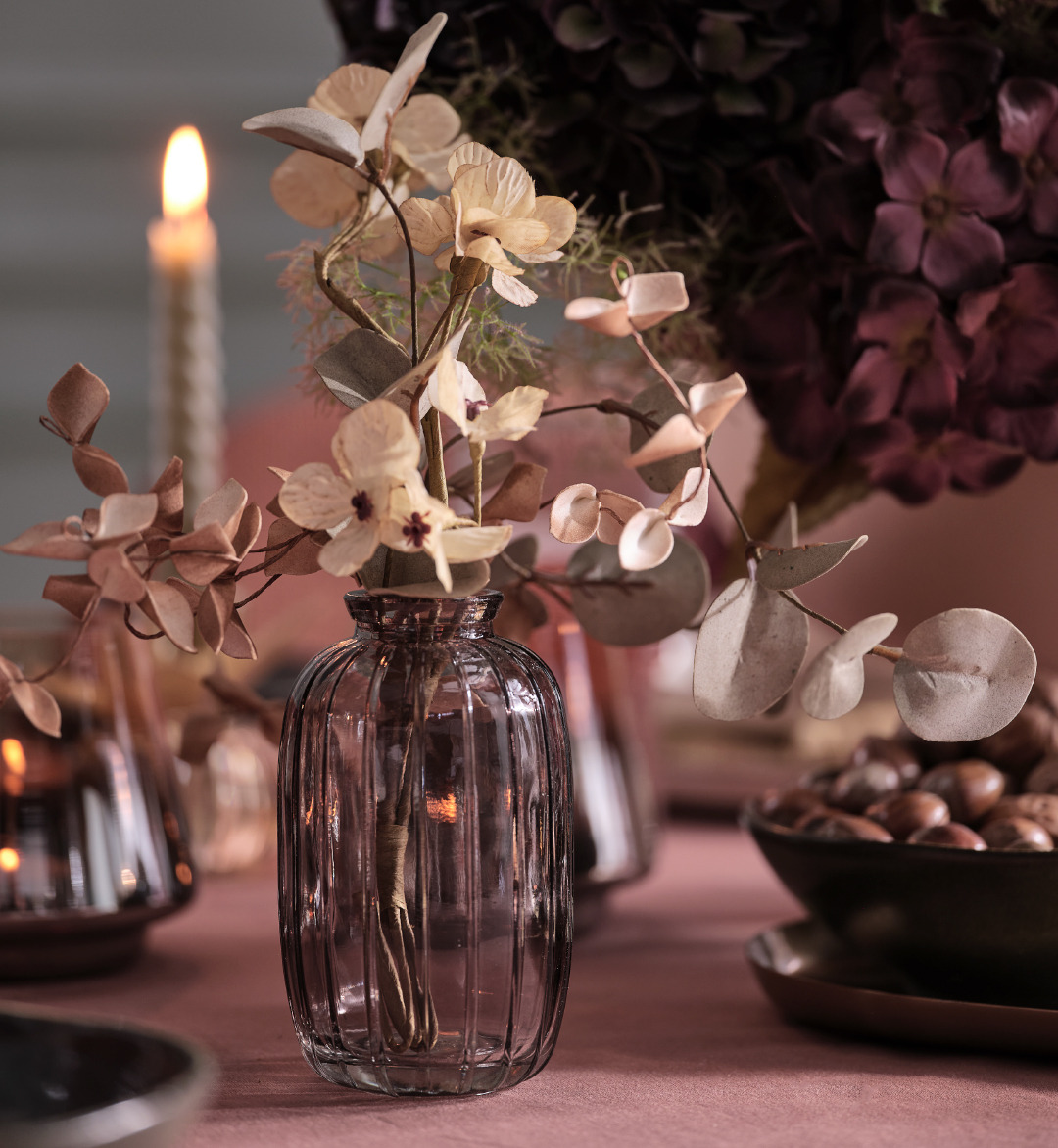 Grijze glazen vaas met kunstbloemen op een tafel