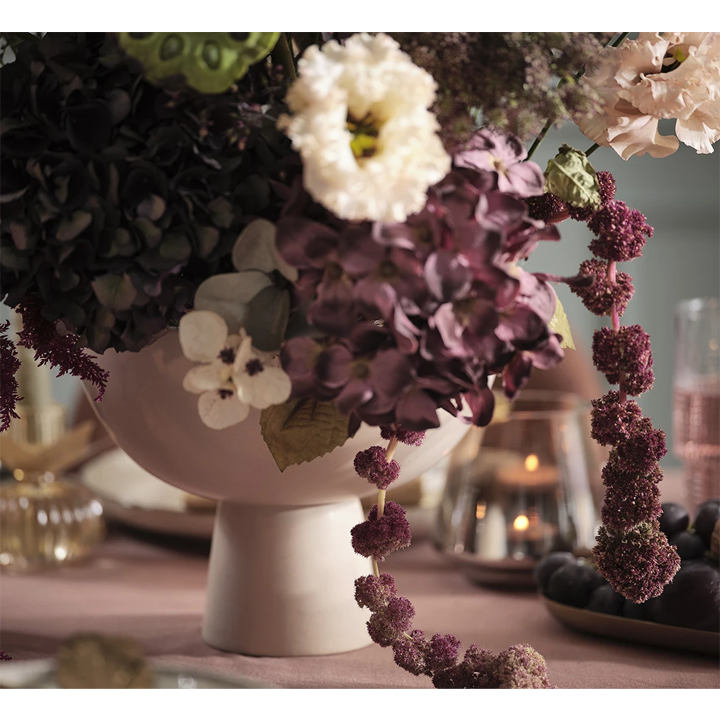 Kom met kunstmatige bloemen op een festivieve dinertafel