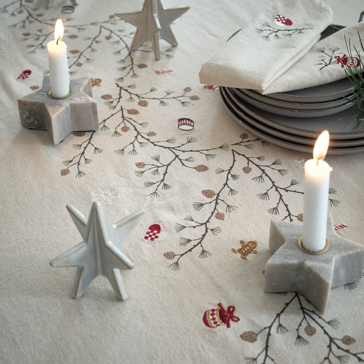 Dinertafel met kerststof, kaars met stervorm, platen en decoratie