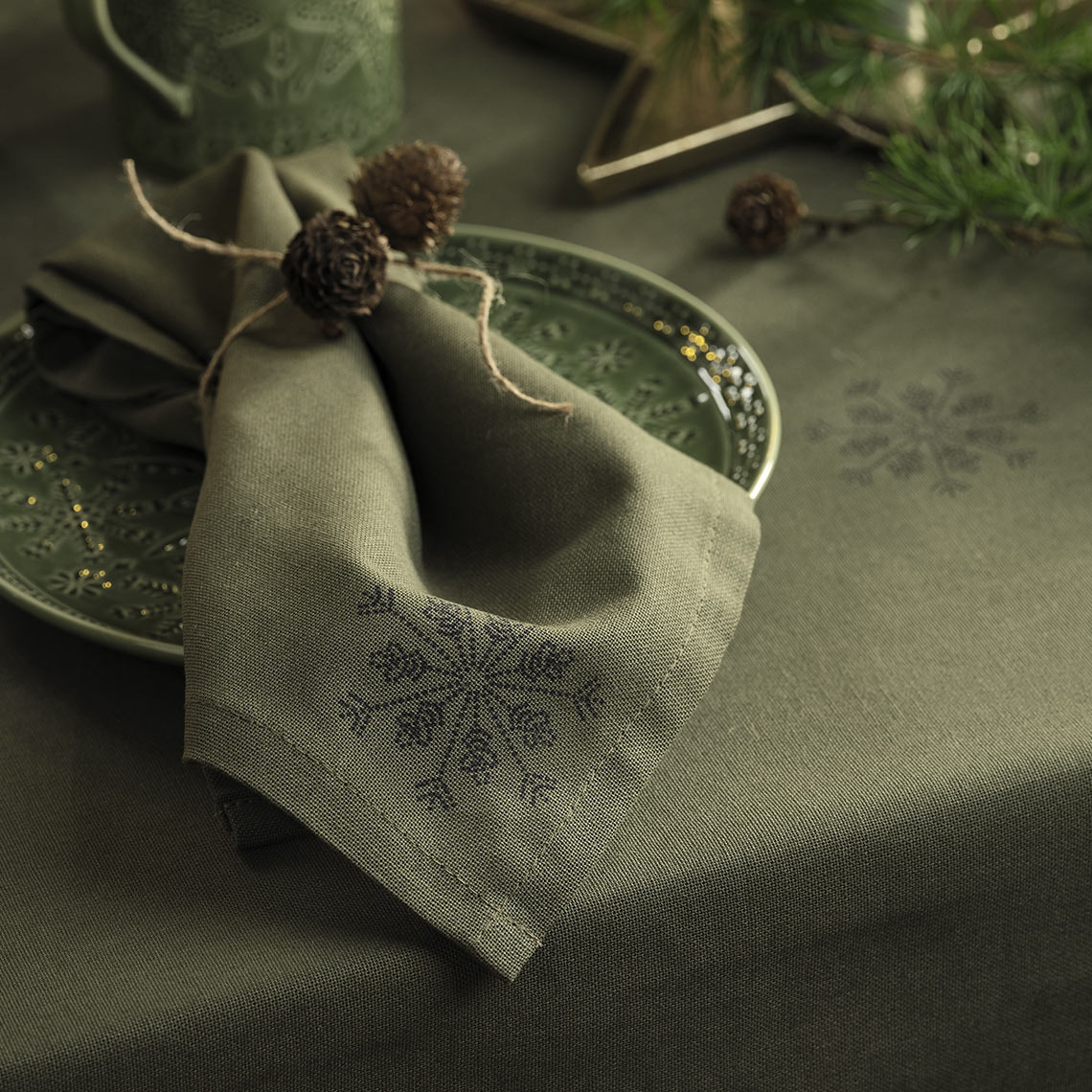 Groene kersttafelkleed en kerstservet op een groen bord