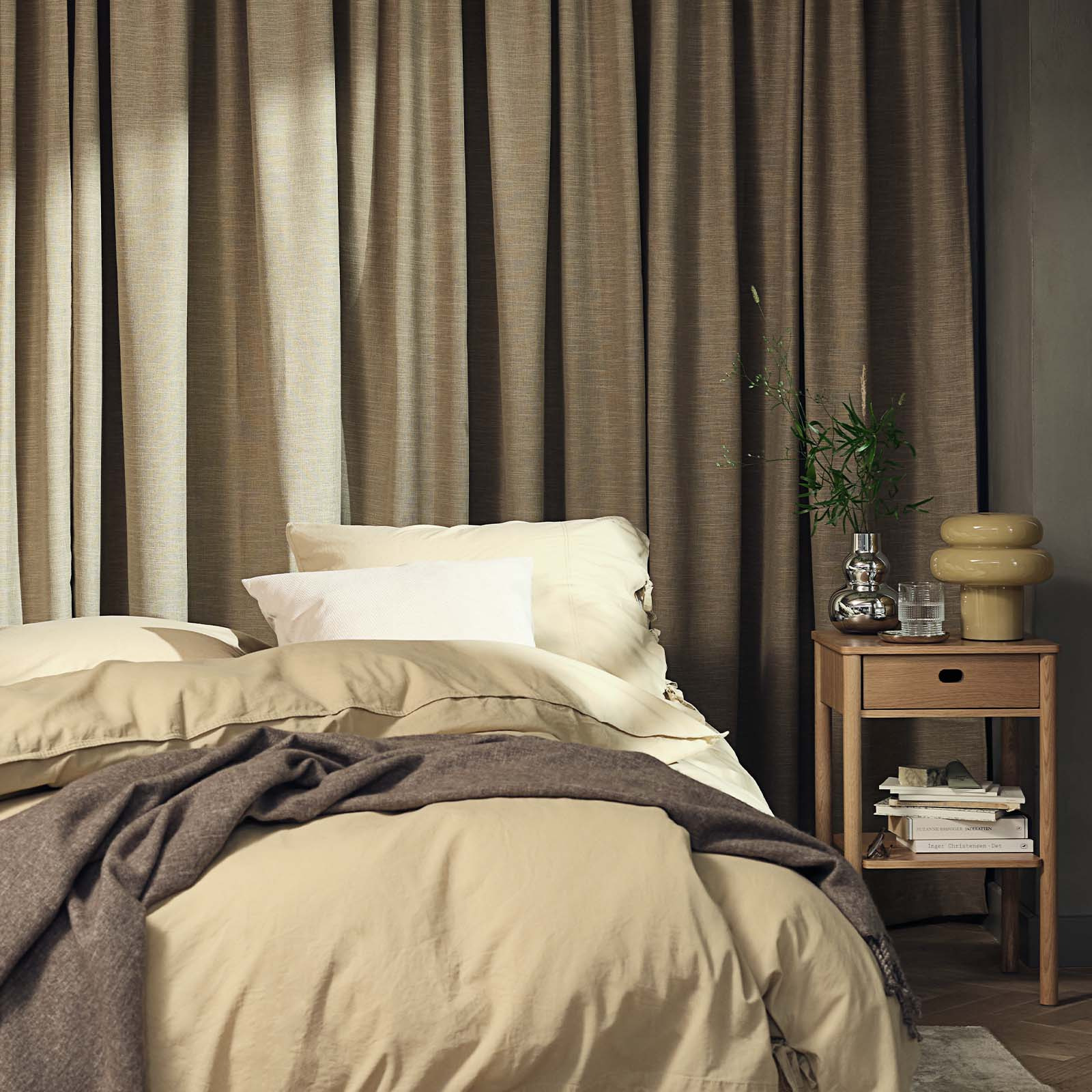 Slaapkamer met een groot, zwaar gordijn in kaki kleur