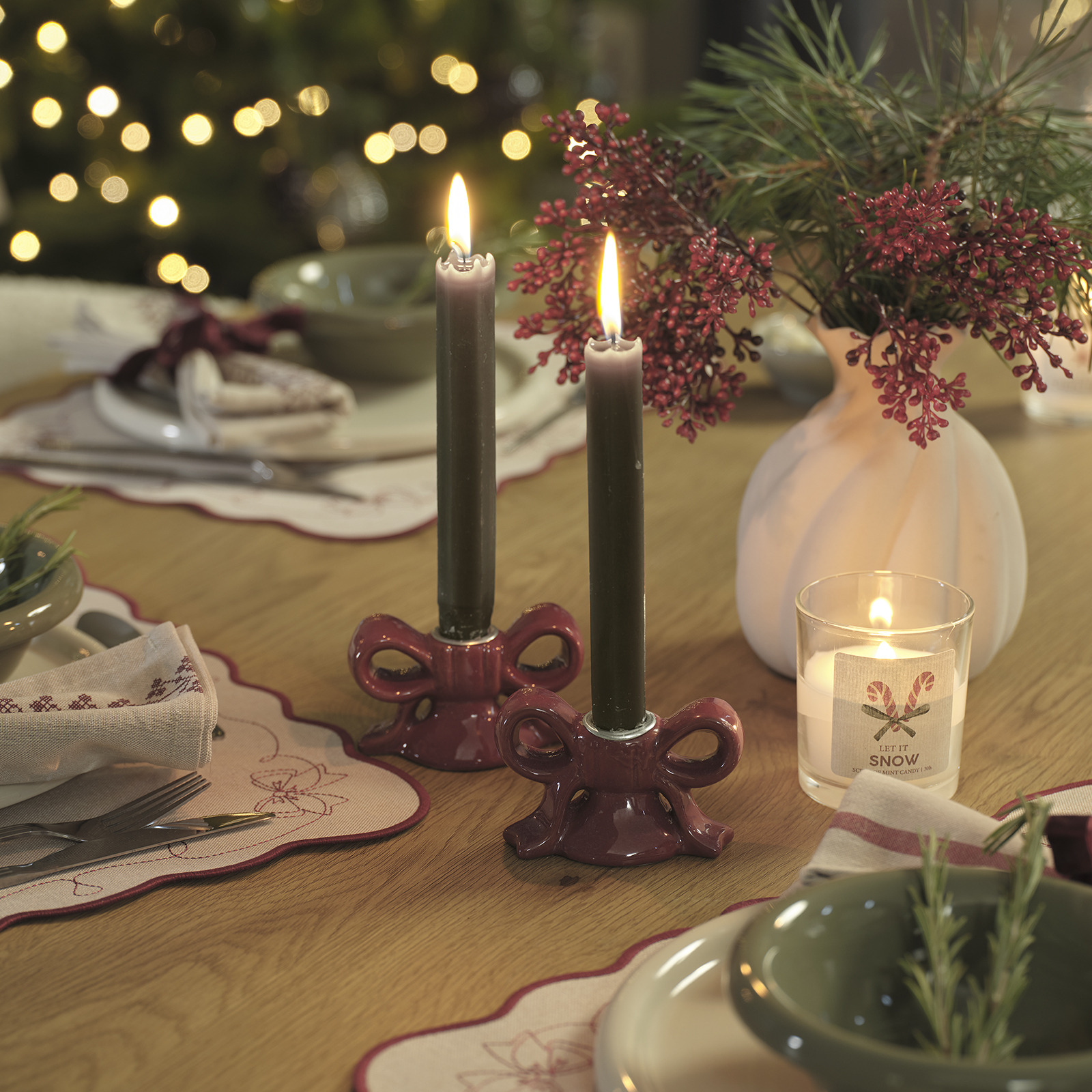 Kersttafel versierd met een vaas met kunstbloemen en kandelaars met kaarsen