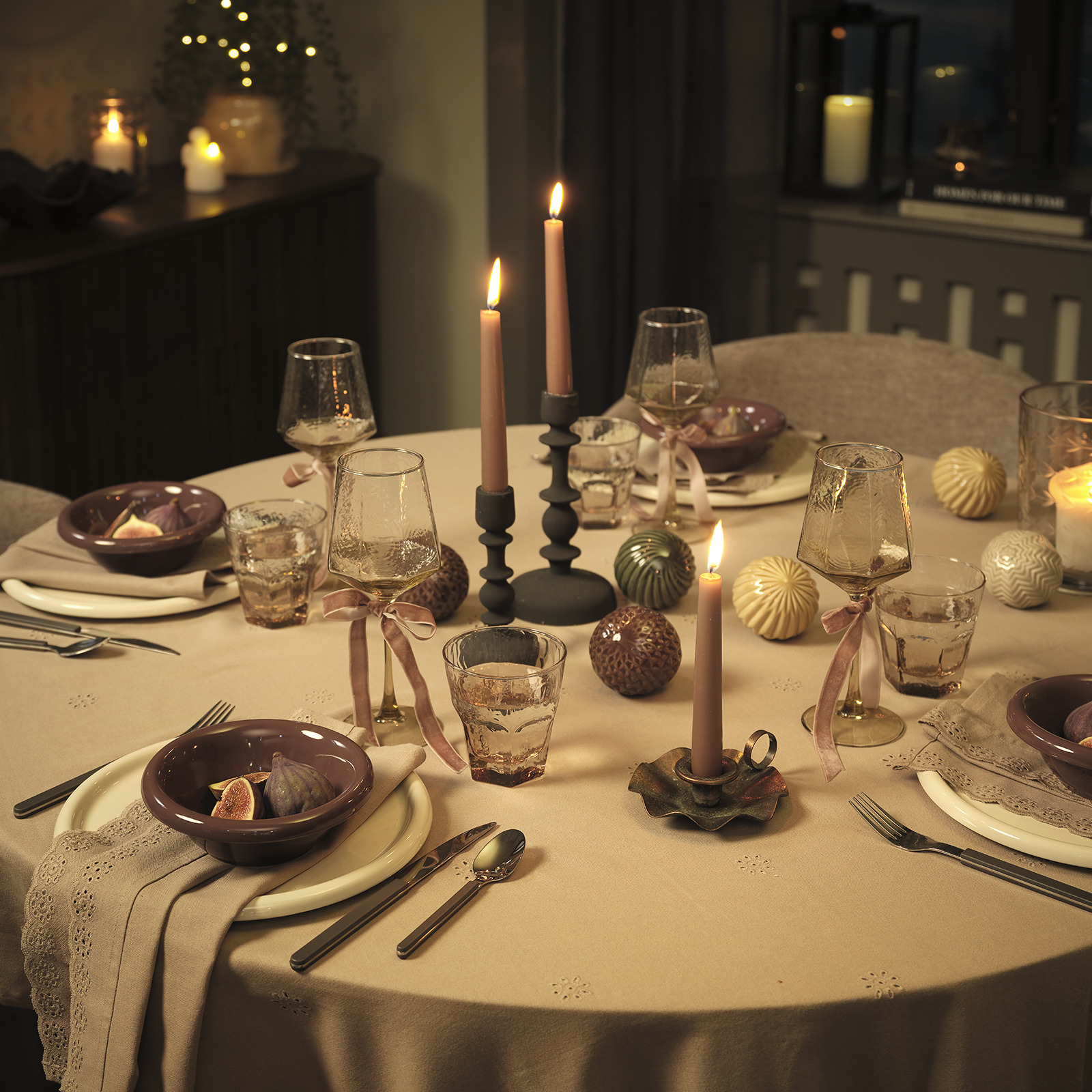 Een dinertafel bij kaarslicht met borden, kommen, bestek en decoraties