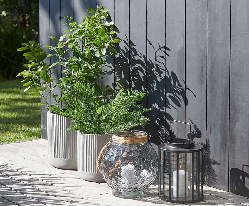 Small and large garden pots and two lanterns on a sunny patio 