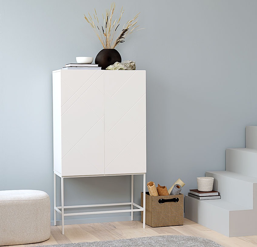 LADBY kast met off-white poef OREBO en FREJ jute opbergmand Witte kast met een zwarte vaas en andere decoratie, een witte poef, en een opbergmand van jute