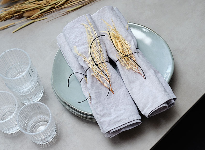 Tafel met borden, glazen en servetten, gedecoreerd met droogbladeren