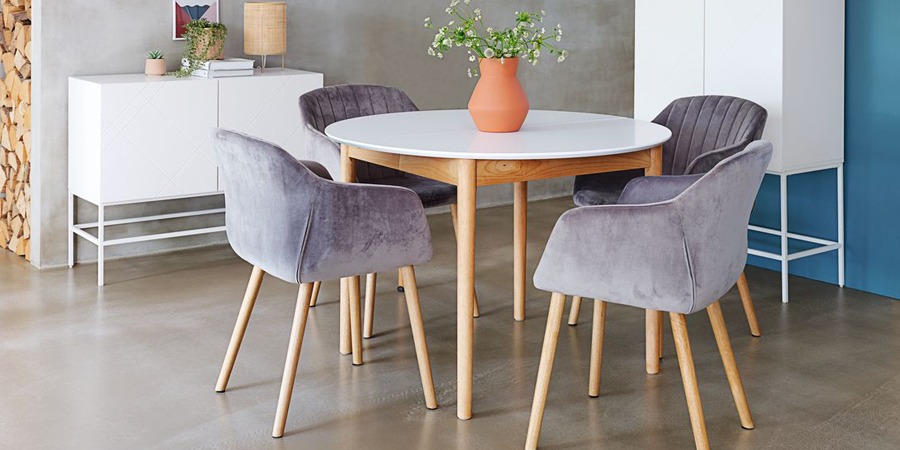 Grijze fluwelen stoel met eiken hout poten aan een ronde witte tafel met eiken hout poten