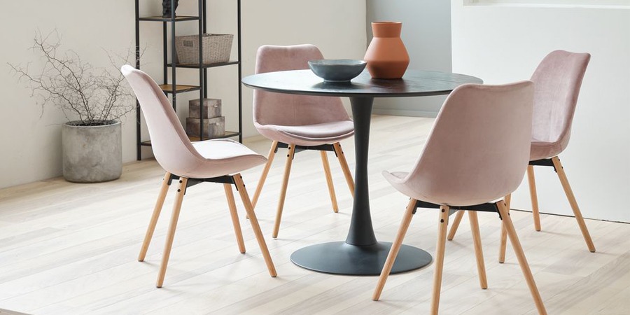 Roze stoel van fluweel aan zwarte ronde tafel