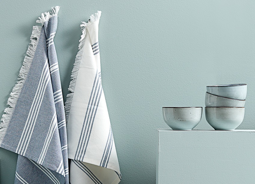 Cotton tea towels hanging next to ceramic bowls 