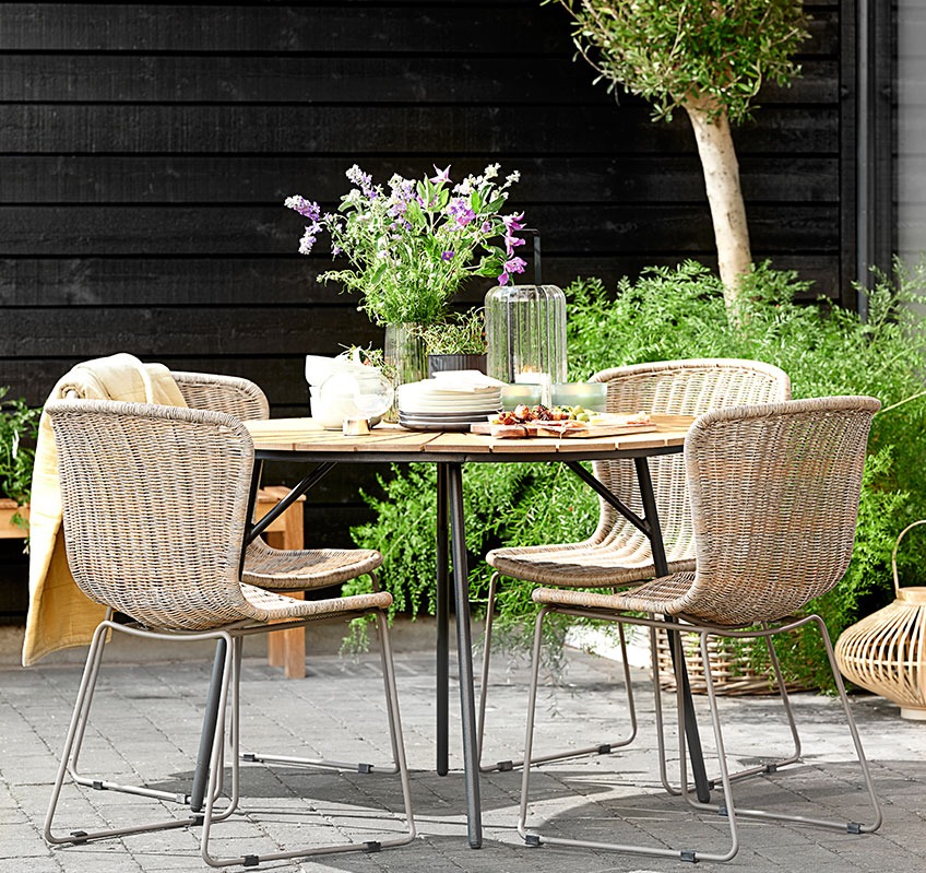 Four stacking chairs around a round garden table on a patio
