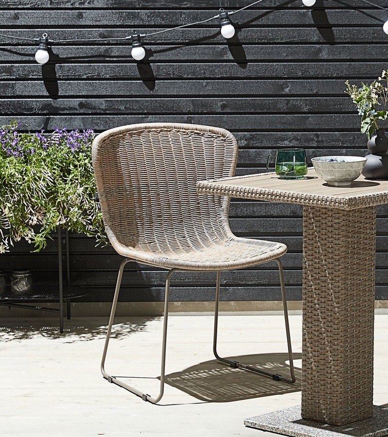 Natuurlijke stoel van polyrotan en staal met een bistrotafel van polyrotan op een terras