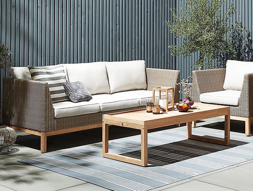 GLAMSBJERG loungeset van polyrotan en teak hout. De loungetafel is volledig gemaakt van gerecycled teak Loungeset met een tafel van gerecycled teak hout