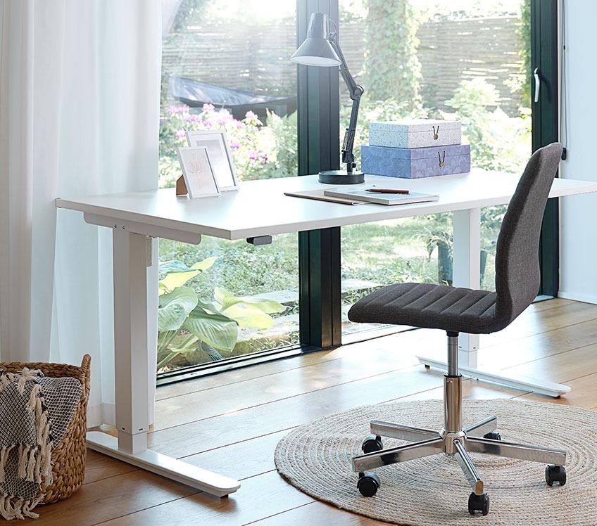 Grijze bureaustoel aan een in hoogte verstelbaar bureau bij een raam