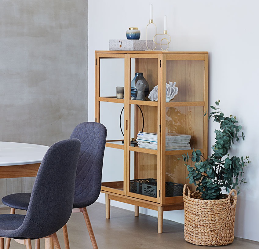 Glazen kast met schappen van glas tegen een witte muur in een eetkamer