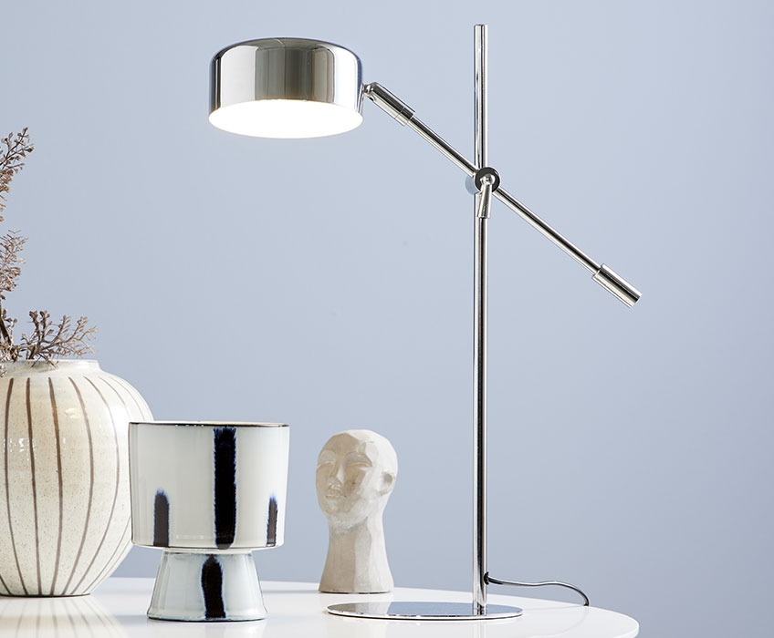 Tafellamp van chroom met woonaccessoires op een witte tafel 
