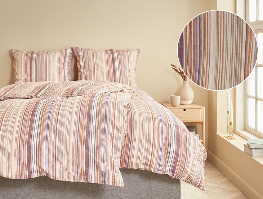 Slaapkamer met twee dekbedden en kussens met een gestreept dekbedovertrek