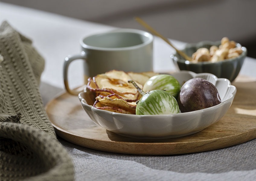 SIMON kom en GERNER houten dienblad Dienblad van hout met grijze kom gevuld met fruit op een sofa