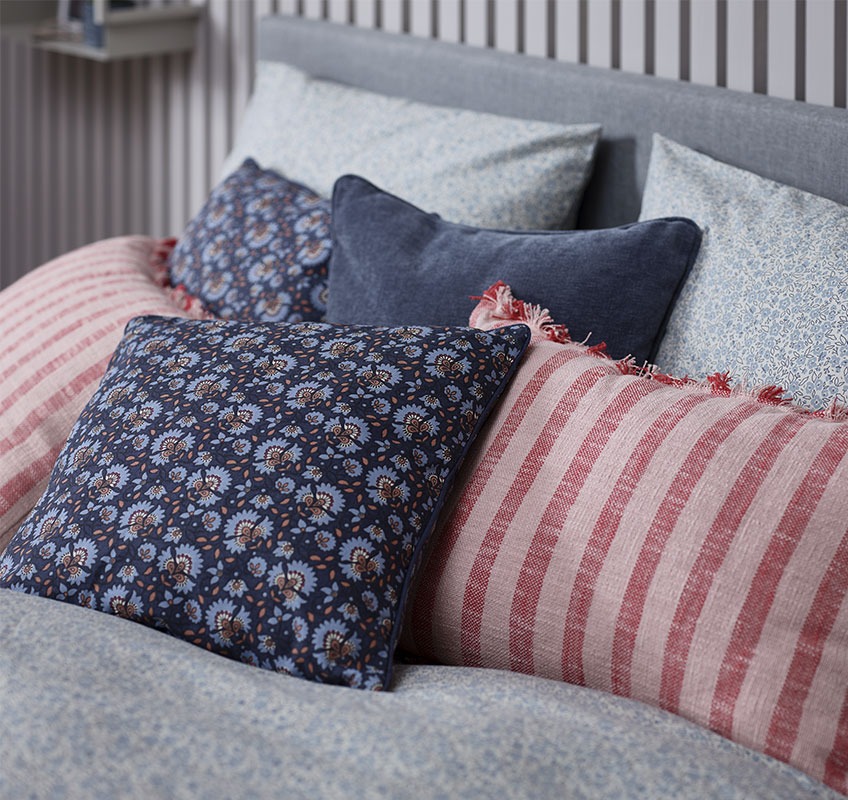 Bed met decoratieve kussens in rode en blauwe nuances