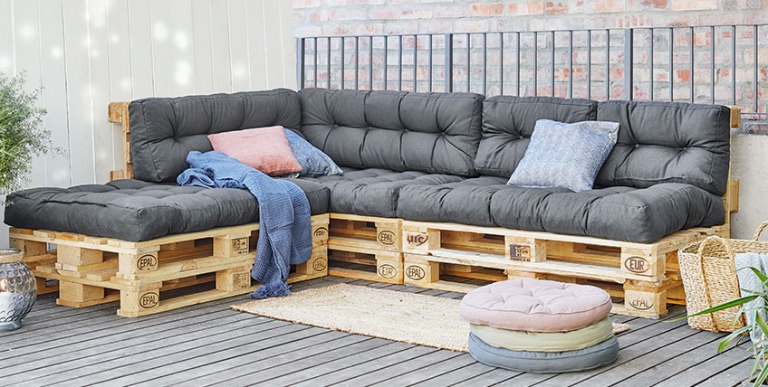 SKJERPE rugkussens zijn verkrijgbaar in twee maten Grote hoekbank van pallets met open uiteinde op een patio