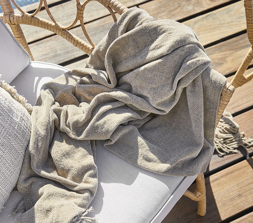 loungestoel met kleed in khaki op een houten terras 