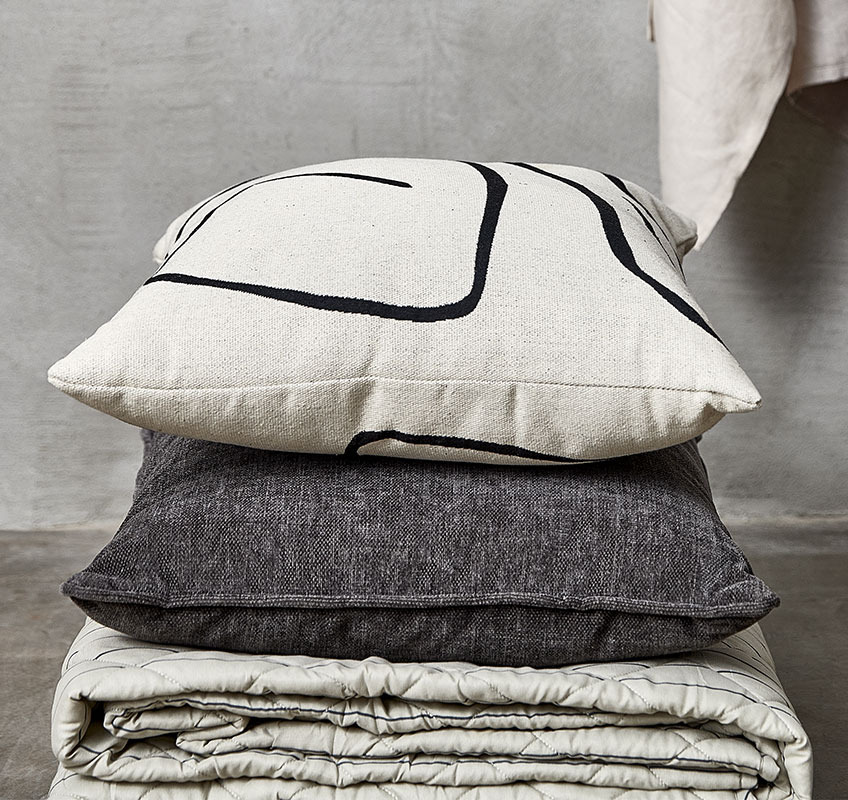 Gewatteerde deken en twee kussens in de kleuren wit, beige en grijs