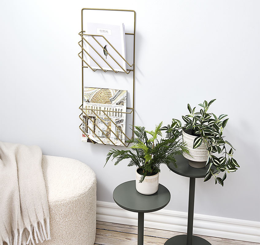 Twee plantenstandaarden in groen en gouden tijdschrifthouder aan de muur