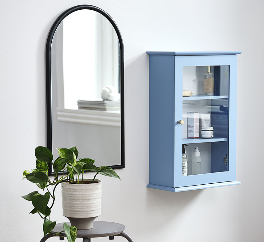 Mirror with black frame next to small wall cabinet 