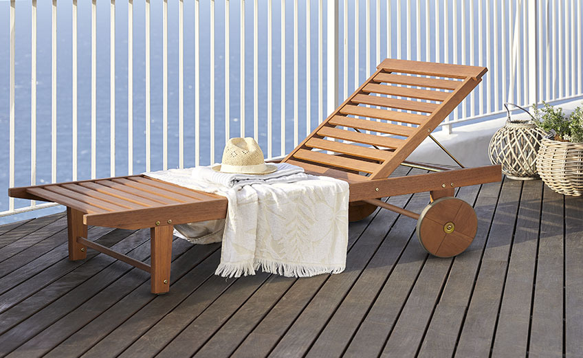 Wooden sun lounger with wheels on a balcony by the ocean