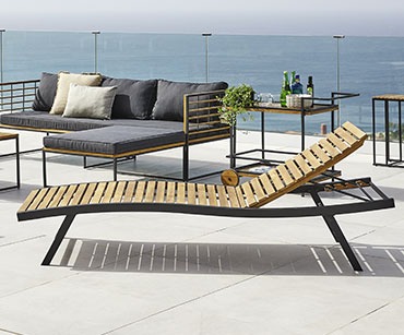 Ligbed van hardhout op een terras met een loungeset