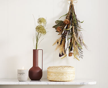 Kaars, vaas met kunstbloem, bamboe opbergdoos en een hangend kunstbloemen boeket