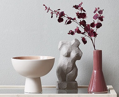 Roze schaal, beeld en een donker roze vaas met een kunstbloem